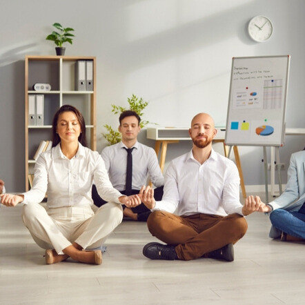 Séance de méditation en groupe dans un environnement professionnel, illustrant la gestion du stress au travail.