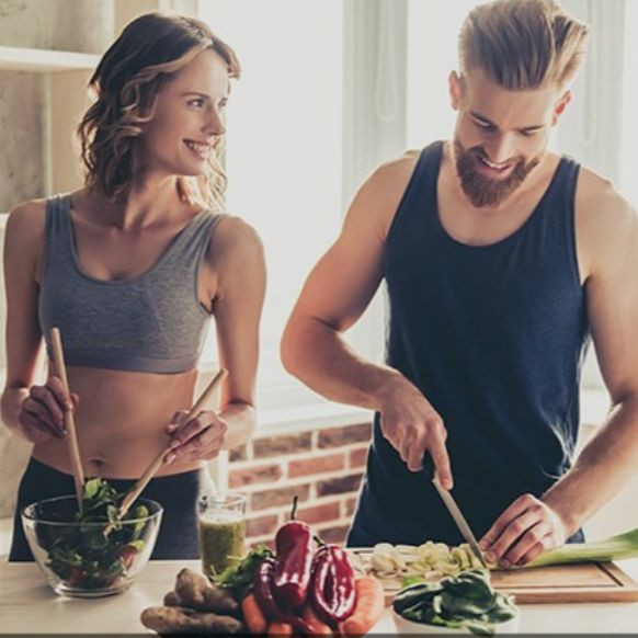 Couple préparant un repas sain avec des légumes frais dans une cuisine lumineuse.