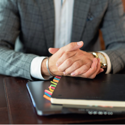 Professional in a suit waiting for an interview or meeting, hands resting on a notebook